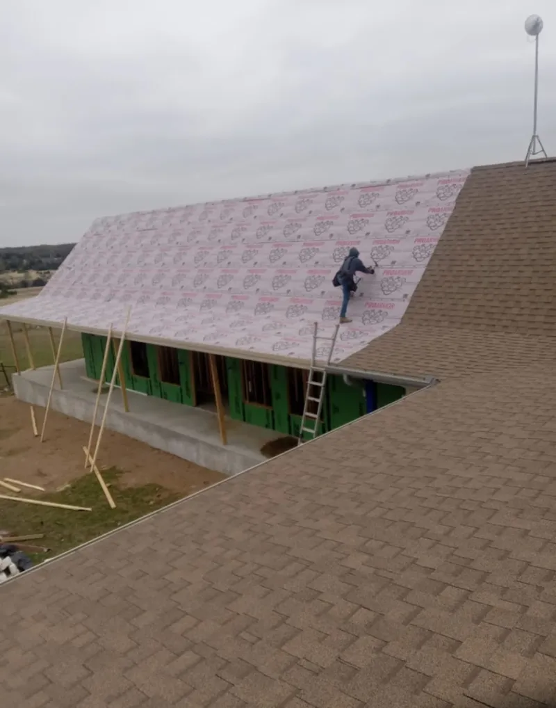 Worker preparing underlayment for a metal roof installation in Natick